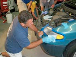Homem detalhando um farol de carro com equipamento de polimento, evidenciando a clareza recuperada.