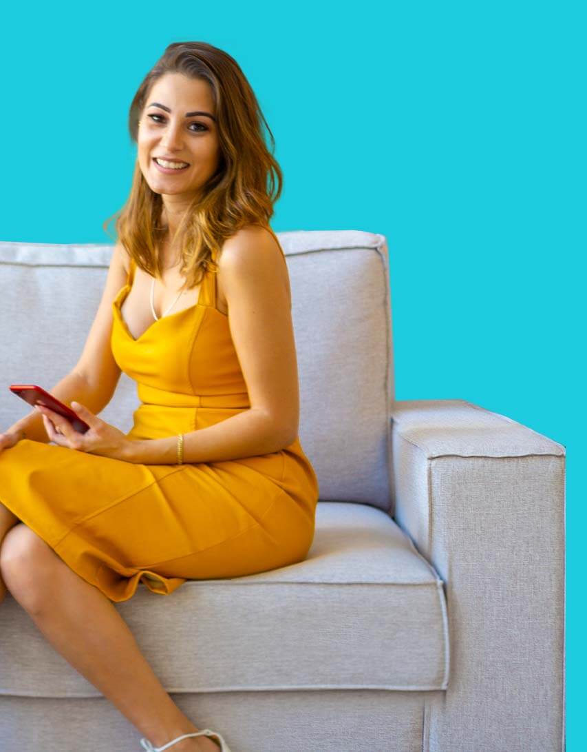 Jovem corretor de imóveis sorrindo e mostrando chaves com casa ao fundo