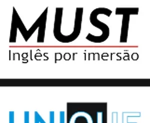 Estudante sorrindo e segurando um livro de inglês com um mapa mundi desfocado ao fundo